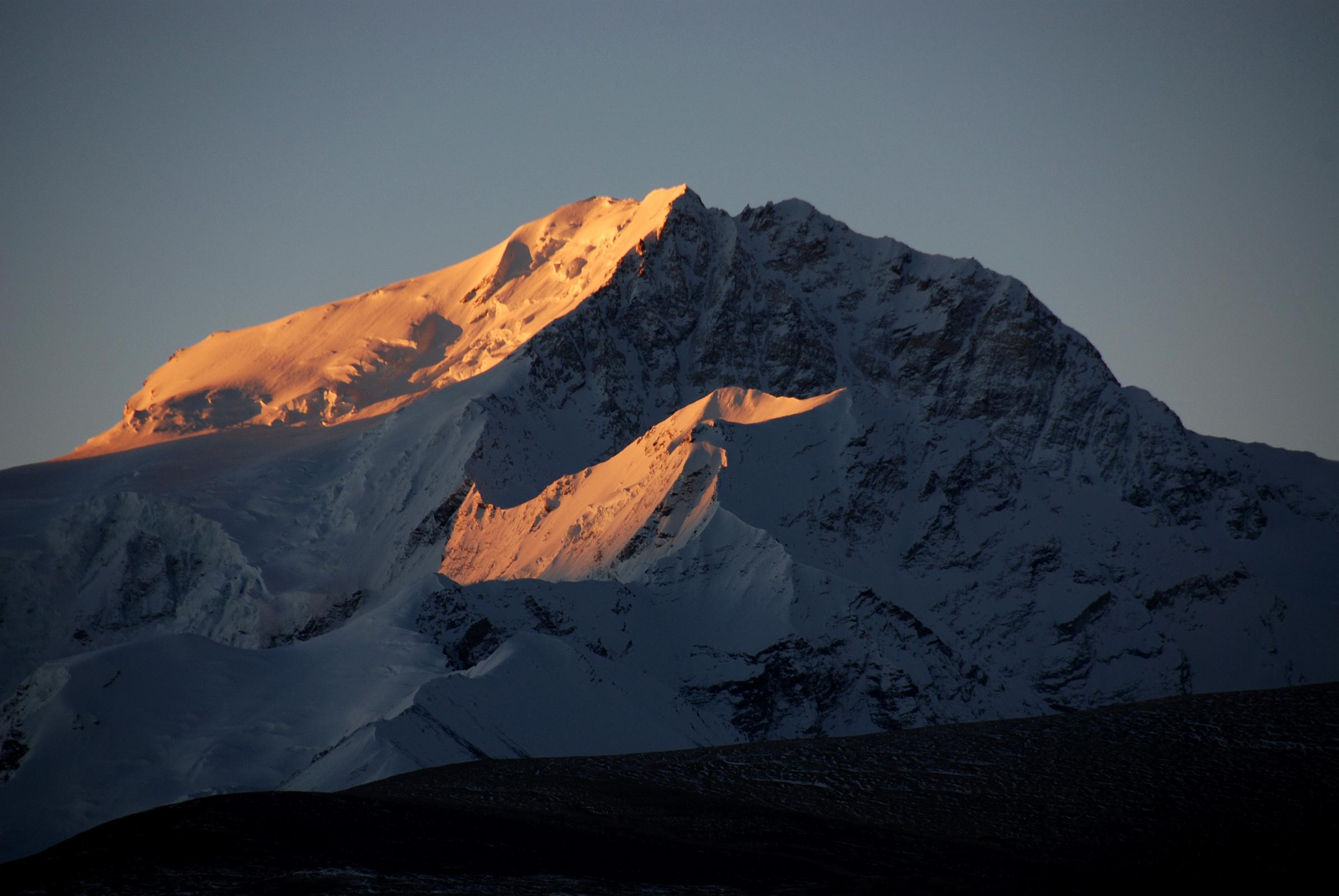 09 Shishapangma East And North Faces And Yebokangal Ri At Sunrise From Shishapangma North Base Camp Shishapangma East Face shines at sunrise from Shishapangma North Base Camp (5029m). The peak with the suns rays just below the Shishapangma North Face is Yebokangal Ri (7365m, Jebo Kangri), which was first climbed by Jerzy Kukuczka and Artur Hajzer on August 29, 1987.